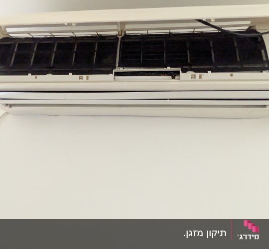 מזגן מותקן על קיר לבן עם מכסה פתוח